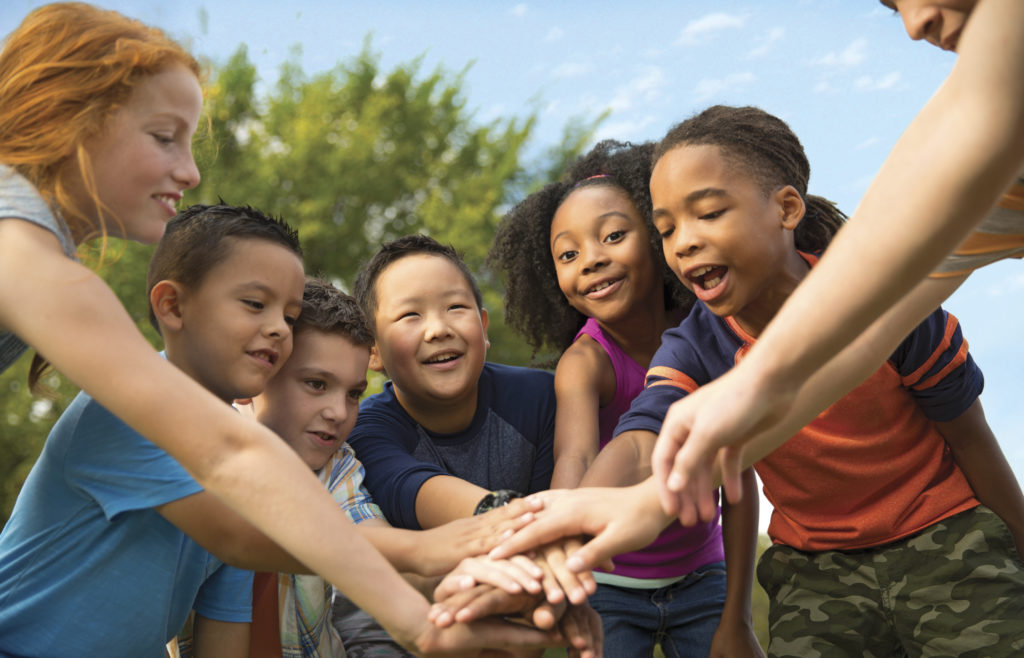 Diverse group of kids with hands on top of each other in center
