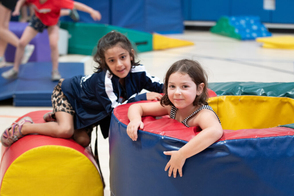 Two girls play in big brightly colored gym apparatus