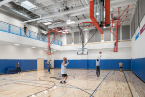 Shooting hoops in the GBYMCA gym with someone running on track above