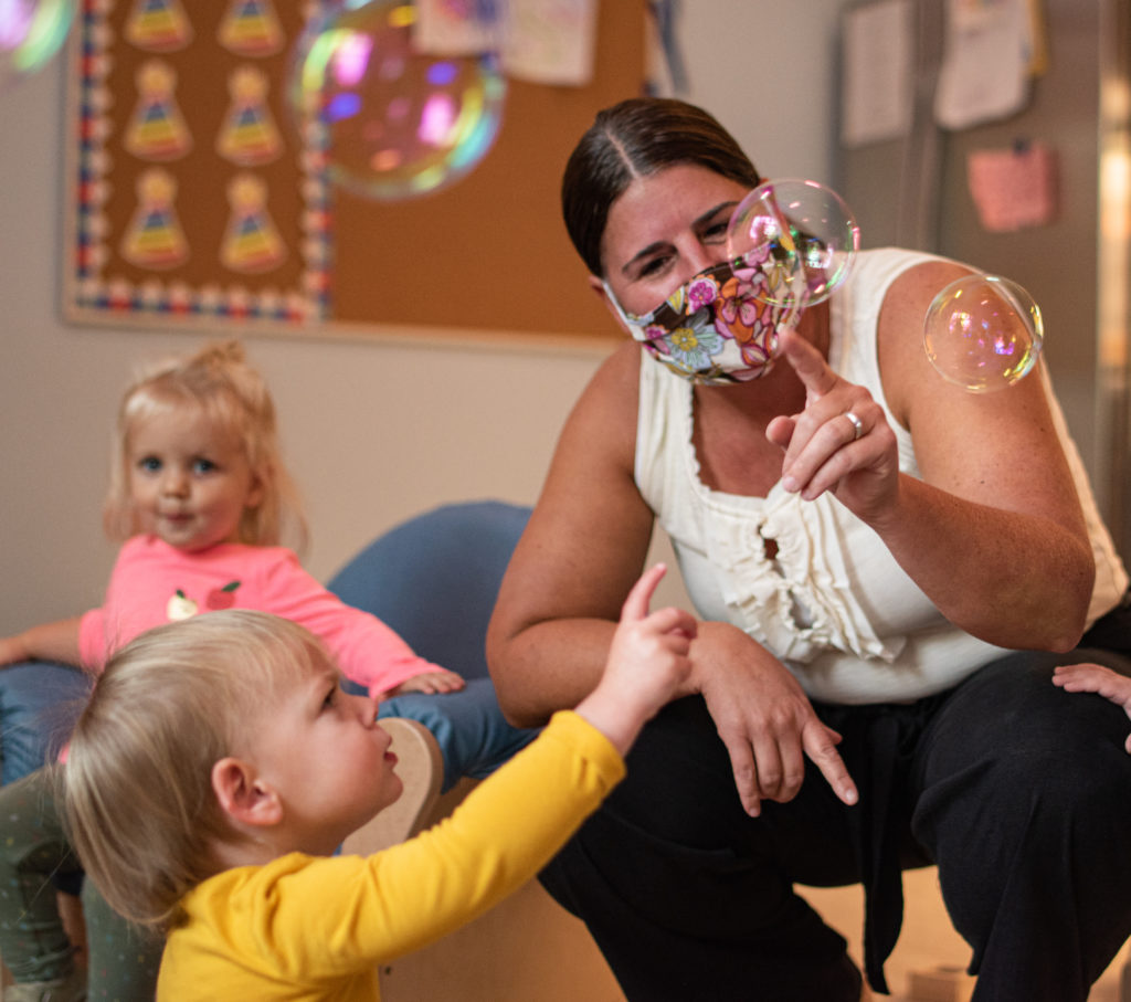 Early Child Care Director playing with bubbles and toddler