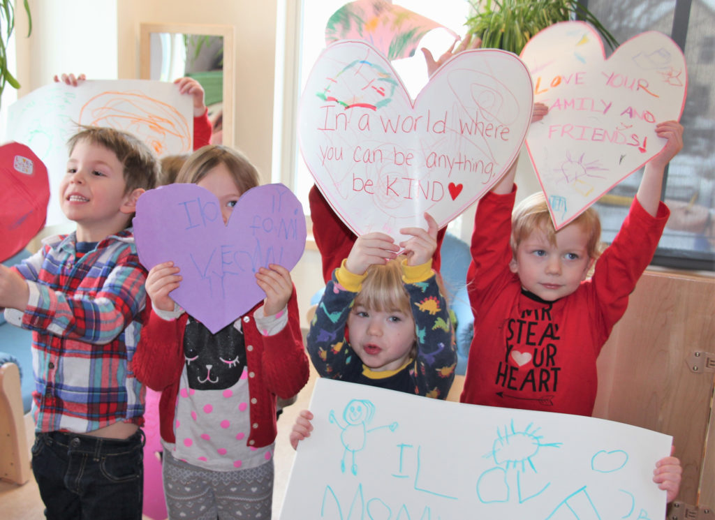 Preschoolers holding up signs they made for Valentines Day