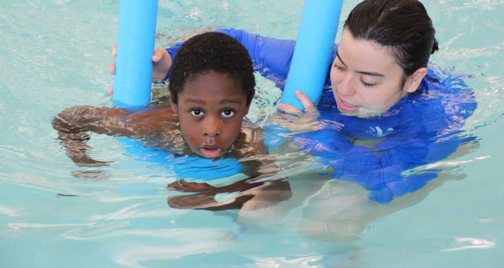 Aquatics staff helping boy learn to swim