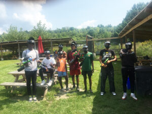 Group of teen males with paintball guns and masks, outside on a summer day